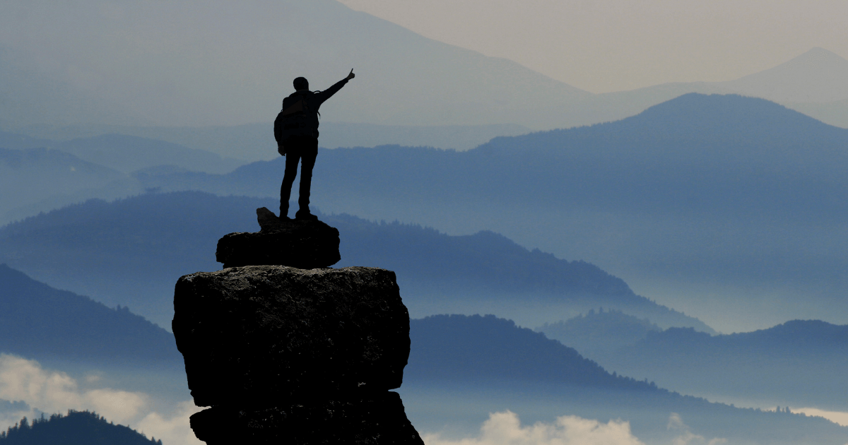 Person achieving goals by reaching the top of the mountain